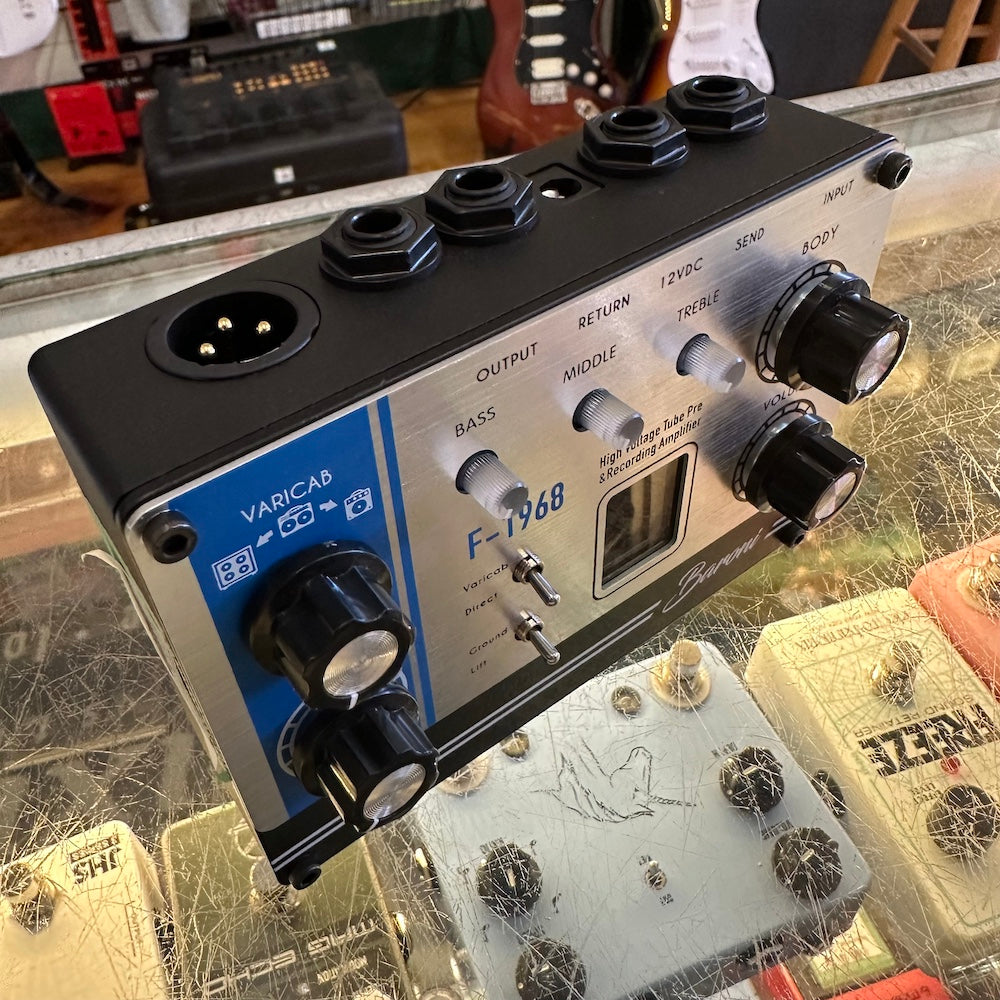 Guitar effects pedal with knobs and connectors on a glass surface