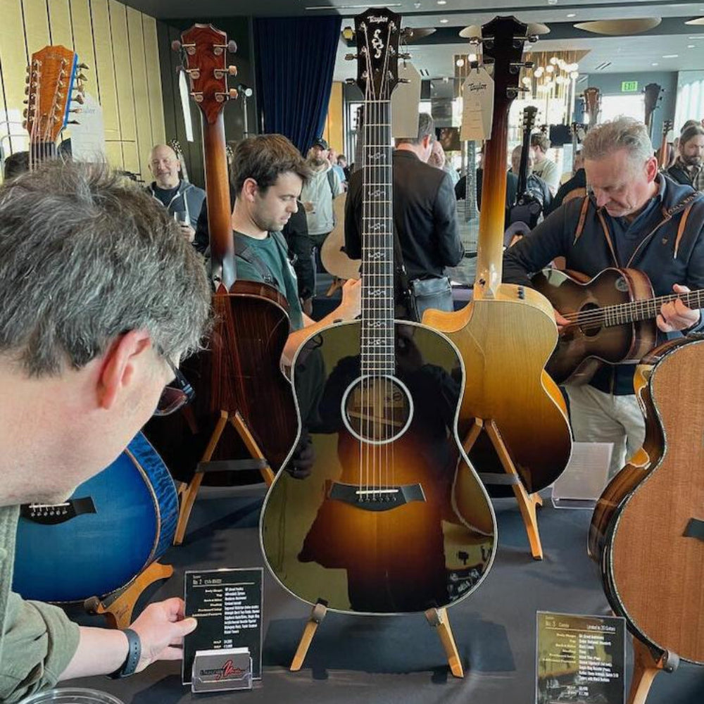 Guitar display with multiple acoustic guitars on stands in a showroom setting.